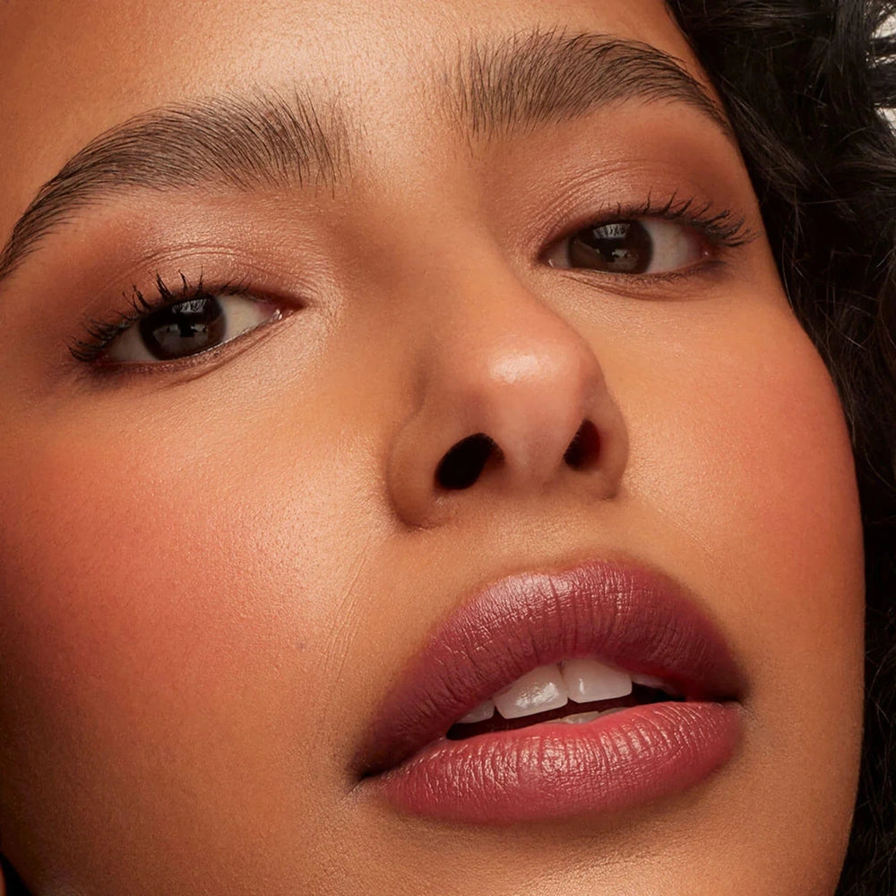 Close-up of a model's face showcasing a matte dusty rose pink lipstick on her lips.