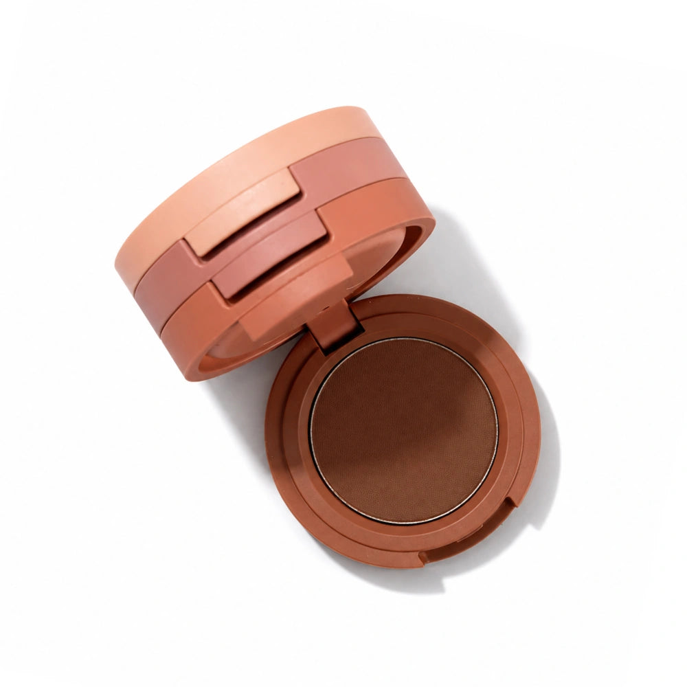 An open round makeup compact showing a warm medium-brown pressed powder, with a matching brown lid resting beside it on a clean white background.